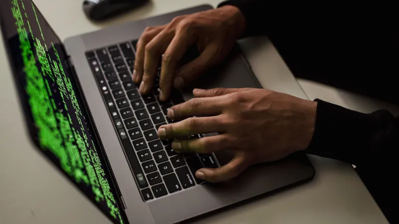 AI agent prompt injection: hands typing on a laptop with green attacker code cascading down the screen